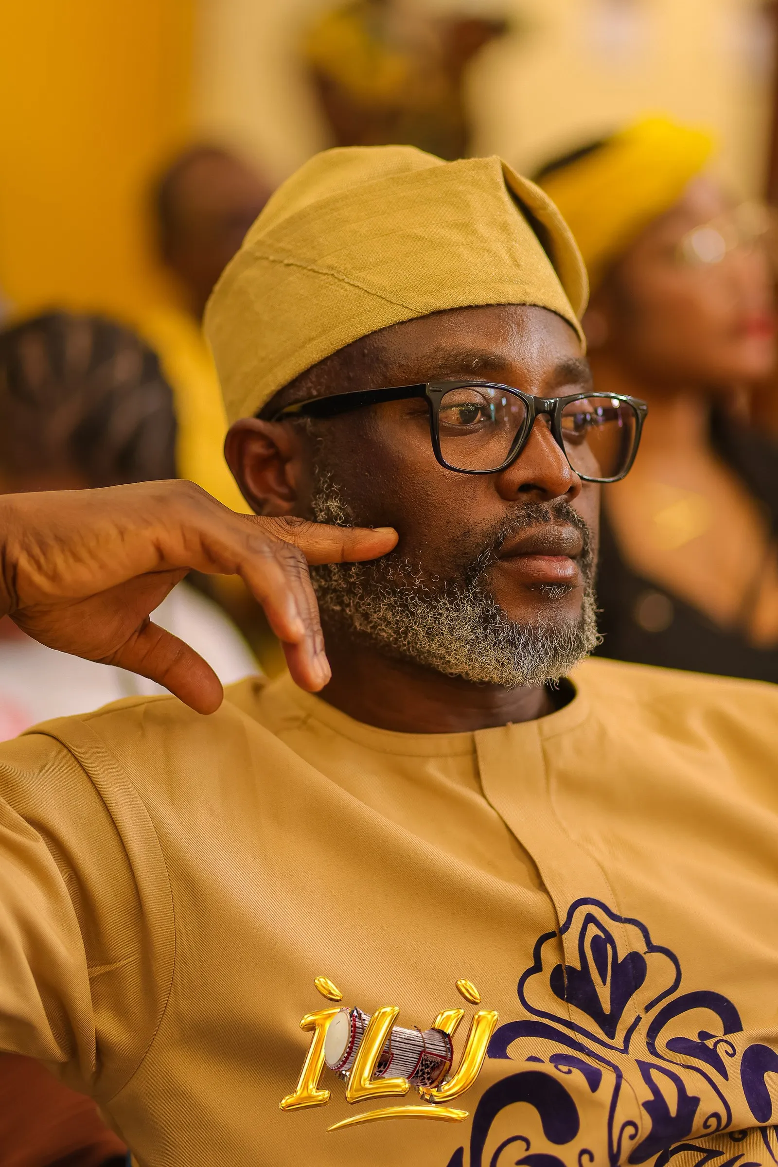 A guest in aṣọ-òkè, listening